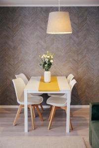 a white dining room table with white chairs and a vase of flowers at Cotroceni Accommodations Upstairs in Bucharest