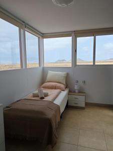 Un dormitorio con una cama en una habitación con ventanas. en Villa Sol Naciente, en Lajares