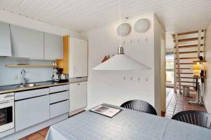 una cucina con mobili bianchi e un tavolo con sedie di Unique Holiday Apartment In Old Skagen a Højen