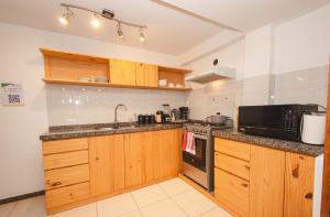Una cocina con gabinetes de madera y microondas. en Hotel and Country House Valle Sagrado de los Incas, en Huaran