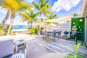 a patio with a table and chairs on the beach at Cottage Beach House NBBC 2, beachfront, pools in Baie Nettle