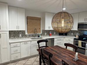 cocina con armarios blancos, mesa y lámpara de araña en The Retreat at Santa Rosa Beach Bungalow E, en Destin