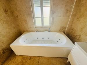 Una bañera blanca en un baño con ventana. en la vallée du paradis studio avec balnéothérapie en campagne, en Alette 49 fotos más