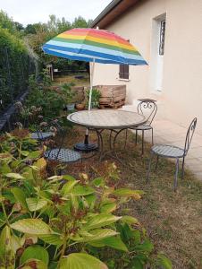 a table and chairs with a colorful umbrella at Calme, proche Bordeaux - jardin et chats in Bassens