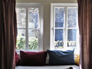 a couch with pillows in front of a window at Little Brook Cottage in Hebden