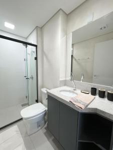 a bathroom with a toilet and a sink and a mirror at Flat Alto e Completo Com linda Vista da Cidade in Campo Grande
