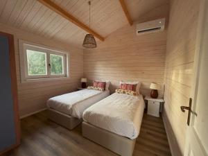 two beds in a room with wooden walls at Cabana in Sesimbra