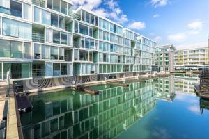 a building with a reflection in a body of water at QV Stays Modern City Retreat in Auckland