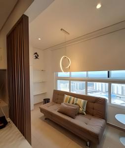 a living room with a couch and a large window at Loft Moderno perto da Faculdade in Mogi das Cruzes