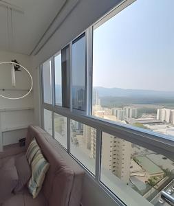 a living room with a couch and a large window at Loft Moderno perto da Faculdade in Mogi das Cruzes