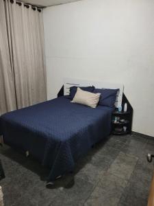 a bedroom with a bed with blue sheets and a pillow at Linda casa para final de semana com churrasqueira in Praia Grande