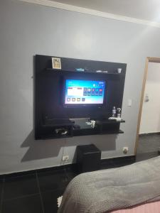 a flat screen tv on a wall in a bedroom at Linda casa para final de semana com churrasqueira in Praia Grande