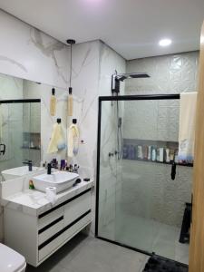 a bathroom with a glass shower and a sink at Linda casa para final de semana com churrasqueira in Praia Grande