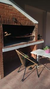 a brick fireplace with a chair and a table at Las Gemelas 3 - Villa Elisa in Villa Elisa