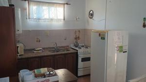 a kitchen with a white refrigerator and a sink at Las Gemelas 3 - Villa Elisa in Villa Elisa