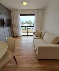 a living room with a white couch and a large window at Mogi das Cruzes: Perto de Tudo, Conforto Total in Mogi das Cruzes