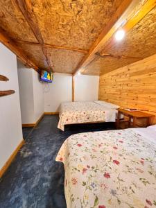 a room with two beds and a table and a tv at FRANKFURTER HOF FAMILIAR Oxapampa in Oxapampa