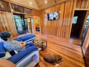 a woman sitting on a couch in a living room with a dog at La casa del Erizo in Oxapampa