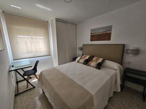 a bedroom with a bed and a desk and a window at Apartamento Reyes Católicos in Córdoba