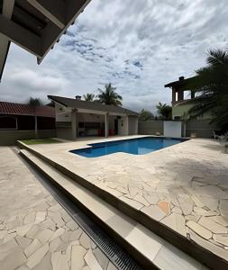a swimming pool in front of a house at Casa na Morada da Praia - Q83 in Bertioga