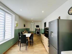 a kitchen with a table and chairs and a refrigerator at L'Athéna in La Fère