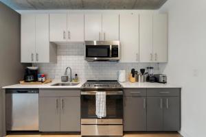 a kitchen with white cabinets and stainless steel appliances at Chic 4-Bedroom with Skyline Views & Amenities in Chicago