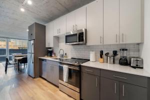 a kitchen with white cabinets and stainless steel appliances at Chic 4-Bedroom with Skyline Views & Amenities in Chicago +48 photos