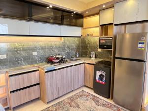 a kitchen with wooden cabinets and a stainless steel refrigerator at شقة فندقية بالزمالك خلف فندق ام كلثوم اطلالة جانبية على النيل in Cairo