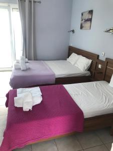 two beds in a room with purple sheets and towels at Drenos Rooms view in Kallithea Halkidikis
