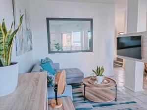a living room with a blue couch and a tv at Ocean Lighthouse - 2 Adults & 3 Kids - Umdloti in Umdloti