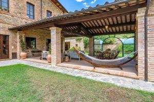 un patio avec un hamac sous une pergola dans l'établissement Podere Siliano Basso, à Castiglione del Lago