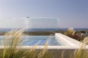 a swimming pool with a fountain and some grass at Amarello Hotel Praia Santo André, Tapestry Collection by Hilton in Santiago do Cacém