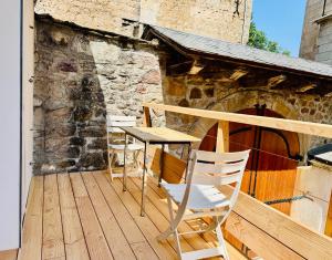 une table et des chaises assises sur une terrasse en bois dans l'établissement Logement entier Chez Léa et Brevia, à Saint-Beauzély