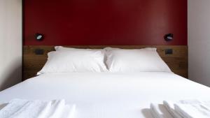 a white bed with a red headboard and white pillows at Morcelli 4 - Bajona in Bormio