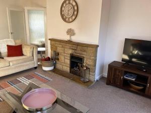 Una sala de estar con chimenea y televisión. en Charming 4-Bed House in Cheltenham Free Parking, en Cheltenham