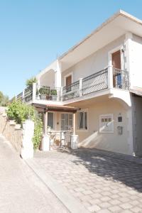 a white house with a balcony and a sidewalk at Apartments Coco in Hvar