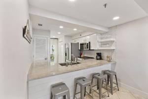 a kitchen with a counter with stools in it at HP 23W Calypso Crossing by 30A Escapes in Rosemary Beach