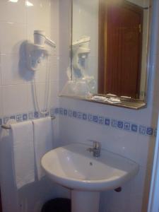 a white bathroom with a sink and a mirror at Hotel Salatia in Alcácer do Sal