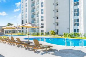 een zwembad met stoelen en een parasol en een gebouw bij 0905 Viva Jaco in Jacó