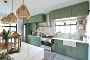 una cocina con armarios verdes y encimeras blancas en Sage Serenity Retreat, en Ciudad del Cabo
