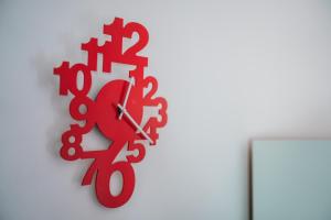 a red clock hanging on a white wall at Violet Red Yellow Apartments in Korčula