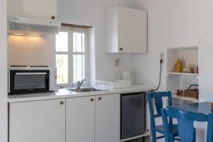 a kitchen with white cabinets and a sink and a microwave at Paraspori in Adamas +7 photos