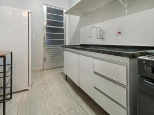 a white kitchen with a sink and a refrigerator at Econômico Plaza Shopping 1 Quarto Central in Carapicuíba +6 photos