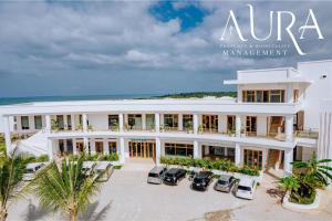 ein großes weißes Gebäude mit davor geparkten Autos in der Unterkunft Aura Space Apartments & Villas Fumba Town Zanzibar in Dambani