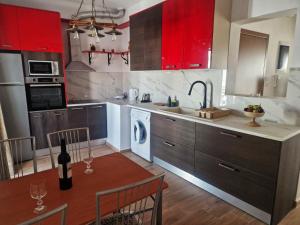 a kitchen with red cabinets and a table with a bottle of wine at Maria House in Kefalos