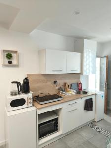 a white kitchen with white cabinets and a sink at studio proche du marché de Noël de Strasbourg in Schiltigheim