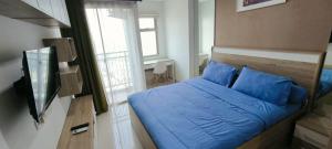 a bedroom with a bed with blue sheets and a window at Springwood Tranquil Studio in Warungmangga +4 photos
