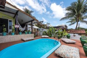 a swimming pool on a patio with chairs and a house at Pousada da Carmô in Fernando de Noronha