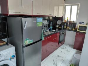 a messy kitchen with a refrigerator and red cabinets at Apartment Sandri in Gjilek