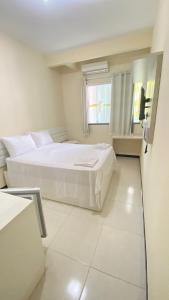 a white bedroom with two beds and a window at Pousada Palladium in Neópolis